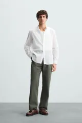 Camisa de algodón blanco con efecto arrugado, cuello mao (tira) y manga larga con puño abotonado. Presenta un corte relajado (relaxed fit) y cierre frontal de botonadura.