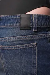 Pantalón de jean azul oscuro de corte ancho con cadena decorativa en la cintura.