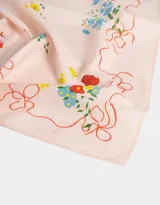 Pañuelo cuadrado de algodón color blanco con estampado de flores rojas, azules y amarillas, y ribete ondulado rojo.