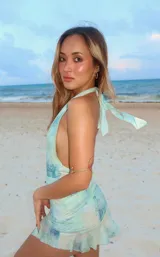 Minivestido celeste con estampado difuminado, escote halter con abertura en V y falda con volados. Presenta un aplique de estrella de mar en el centro.