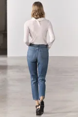 Jeans de tiro medio con corte recto, color azul denim con efecto lavado. Cuenta con cinco bolsillos, trabillas en la cintura y cierre frontal con cremallera y botón metálico.
