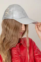 Gorra de cuero ovino color camel, confeccionada a mano, con bordado del monograma "PEC" en hilo blanco en el lateral.