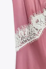Vestido midi de satén color rosado, con escote en V, tirantes finos regulables y detalle de puntilla blanca en el escote.