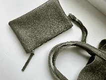 Cartera tipo tote bag color bordó, confeccionada en cuero con textura granulada. Tiene doble asa corta de mano y asa larga extraíble con diseño de tachas para usar como bandolera.