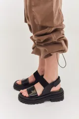 Sandalias de cuero color marrón con plataforma y suela track. Presentan dos tiras anchas, una de cuero liso y otra con textura tipo piel de reptil.