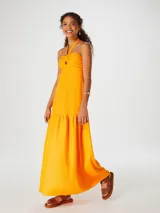 Vestido largo naranja con escote halter y detalle de nudo en el pecho.
