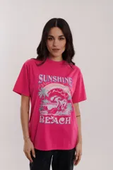 Remera de algodón en color fucsia, con estampado gráfico de olas y texto en la parte frontal.