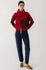 Sweater de punto rojo con cuello alto, mangas largas y diseño con apliques marrones y cordones.