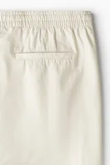 Short color crema de lona de algodón suave, con cintura elástica con cordón para ajustar, bolsillos al bies y un bolsillo insertado atrás. Corte estándar.