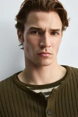 Cárdigan de hombre color verde oliva, tejido de punto canalé en hilatura de algodón, de corte regular fit, con cuello redondo, manga larga y cierre frontal con botones.