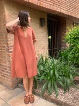 Vestido color ladrillo de tejido de hilo, corte recto, cuello polo con botones y mangas cortas con ribete en color beige.