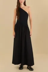 Vestido largo negro con un solo hombro, corte ajustado en el torso y falda acampanada.