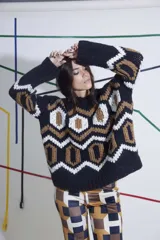 Sweater tejido a mano en lana merino, con cuello redondo y diseño geométrico en colores negro, blanco y marrón. De calce holgado y talle único.