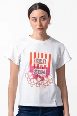 Remera blanca de algodón con cuello redondo y mangas cortas. Estampado frontal con rayas verticales rojas y texto "Sea Sun" con apliques brillantes y flores.
