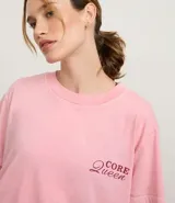 Remera de algodón BCI, color rosa claro con efecto desteñido, de corte oversized y cuello redondo. Presenta un pequeño bordado en el pecho con la frase "Core Queen" en color bordó.
