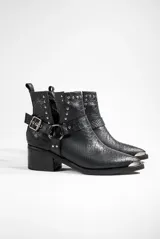 Botas texanas de cuero negro con diseño de piel de cocodrilo, punta metálica plateada, tachas plateadas en el borde superior y hebilla metálica en el lateral. Taco bajo y corte lateral en V.