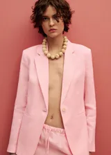 Chaqueta de lino color celeste con cuello de pico y solapas con muesca, cierre frontal con botón, manga larga con puños abotonados, diseño recto, dos bolsillos de ribete en la parte delantera y abertura posterior en el bajo.