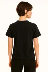 Remera de algodón color crudo con estampado de un labial rojo y texto en color bordó que dice "It's OK to wear lipstick". Corte clásico, cuello redondo y mangas cortas.