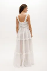 Vestido largo celeste de gasa de algodón con textura liviana. Tiene escote en V con nudo central, breteles con voladitos y frunces en la falda.