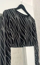 Conjunto de top manga larga y minifalda con estampado de líneas brillantes sobre tela transparente negra.