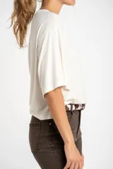 Remera de manga corta, color beige claro jaspeado, con corte al cuerpo y cuello redondo.