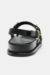 Sandalias planas negras con tiras y hebillas.