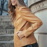 Campera color camel de cuero sintético, con cuello redondo, cierre frontal y bolsillos laterales con cierre.