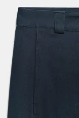Pantalón cargo de tiro medio color azul oscuro, con pierna ancha y bolsillos de plastrón con solapa en las piernas. Presenta cierre frontal con cremallera, botón y ganchos metálicos.