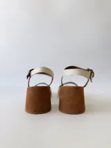 Sandalias de cuero color crudo, con dos tiras anchas sobre el empeine, pulsera al tobillo con hebilla y taco cuadrado de madera.