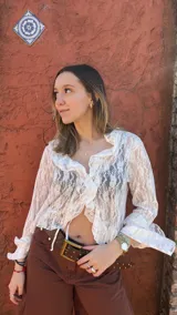 Blusa blanca de encaje transparente con volados en los bordes y mangas globo.