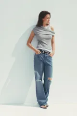 Camiseta blanca con musculosa gris superpuesta con escote asimétrico.