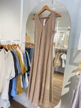 Vestido largo sin mangas, color beige, con escote en V y terminaciones deshilachadas en sisas y ruedo.