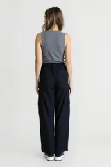 Pantalón negro de tiro alto, corte palazzo y bolsillos laterales.