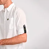 Camisa de popelina verde con cuello abotonado, cierre frontal con botones, bolsillo de parche en el pecho izquierdo, mangas largas con trabillas para enrollar y dobladillo camisero.