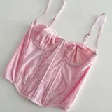 Corset rosa de encaje con breteles finos regulables.