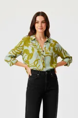 Camisa de viscosa con estampado floral en tonos verde y celeste, corte holgado, cuello camisero y cierre frontal con botones.