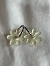 Aros colgantes plateados con dije de flor acrílica color dorado.
