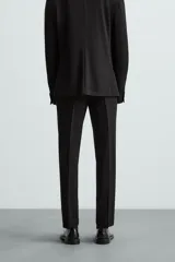 Pantalón de vestir azul marino, de corte slim fit, con bolsillos laterales y traseros. Se ajusta a la cintura con cinturón de cuero marrón.