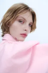 Camisa de popelín rosa de algodón, con cuello solapa, manga larga con puños plisados y volumen en un hombro. Cierre frontal con botones ocultos.