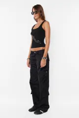 Pantalón cargo color arena de corte recto y tiro bajo, con recortes y presillas dobles en la cintura. Tiene acceso mediante cierre de nylon y botón personalizado, seis bolsillos laterales y dos en la espalda con tapa y botón snap a presión.