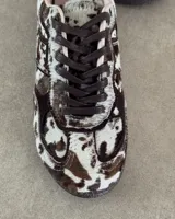 Zapatillas deportivas de cuero vacuno con estampado animal print de vaca en blanco y marrón.