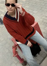 Buzo tejido verde con escote en V, cuello con rayas blancas y azul marino, y puños y ruedo con detalle de rayas.