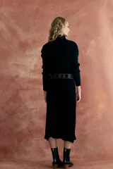 Vestido midi negro de tejido de punto con cuello alto, corte recto y cinturón con apliques metálicos.
