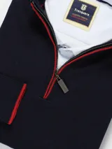 Sweater azul marino de hilo con medio cierre frontal con cremallera y detalles en rojo en cuello y puños.