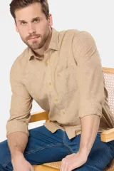 Camisa manga larga color beige confeccionada en lino, con cuello clásico, cierre frontal con botones, bolsillo en el pecho y logo bordado.