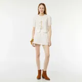 Blusa blanca con mangas cortas abullonadas y detalle de calado. Tiene escote redondo y cierre frontal con cintas.