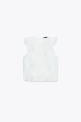 Blusa blanca semitransparente de cuello redondo y sin mangas, con volantes en los hombros y en el frente.