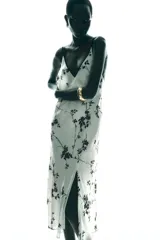 Vestido largo blanco con estampado de flores negras, escote pico y tirantes finos con ribete negro.
