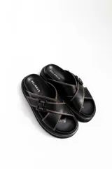 Sandalias de cuero negro con tiras cruzadas y hebilla lateral.