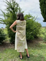 Vestido midi de corte evasé con estampado de hojas en tonos verdes y beige.